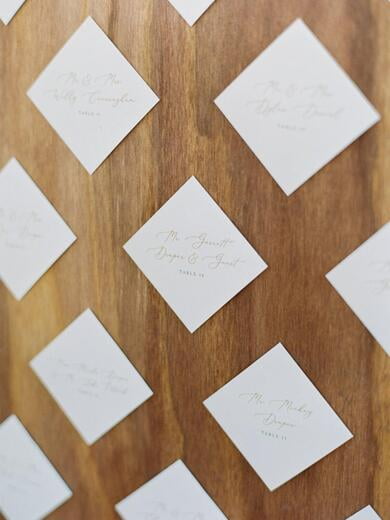 Diamond Shaped Escort Cards on Wooden Backdrop