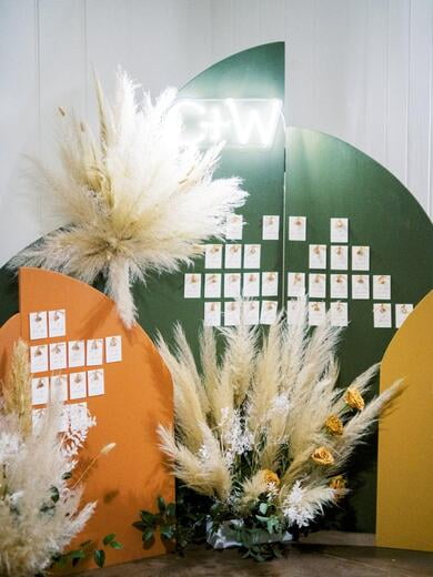 Wedding Escort Cards with Tassel Displayed on Arched Back Drop in Burnt Orange, Mustard and Green