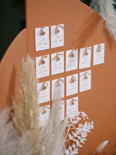 Wedding Escort Cards with Tassel on Arched Back Drop in Burnt Orange