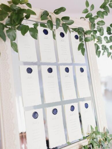 Deckled Edge Escort Seating Signs with Navy Wax Seal on Mirror with Greenery